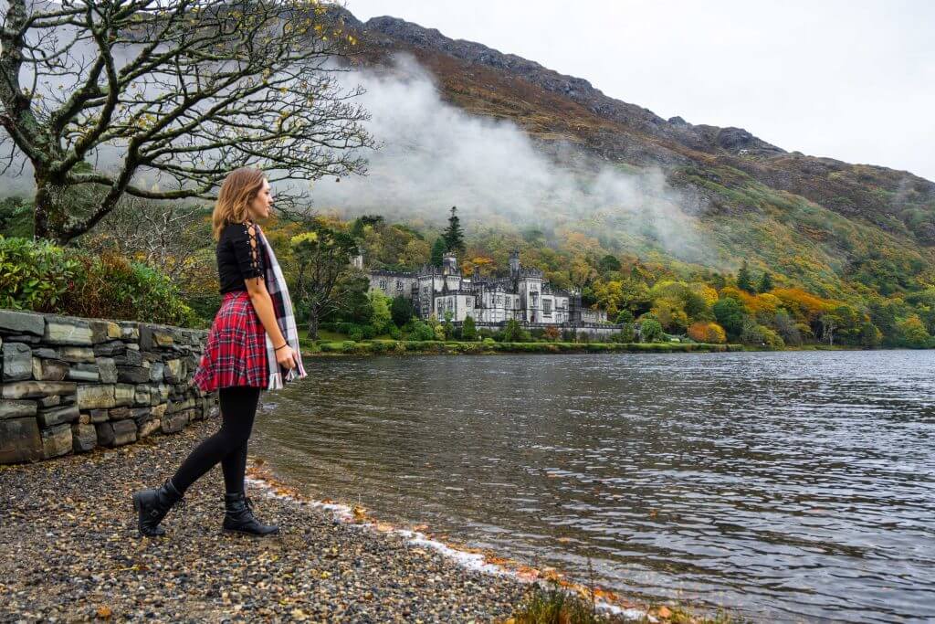 Woman gazing at the misty fall foliage in Ireland on a cool, gray-sky day