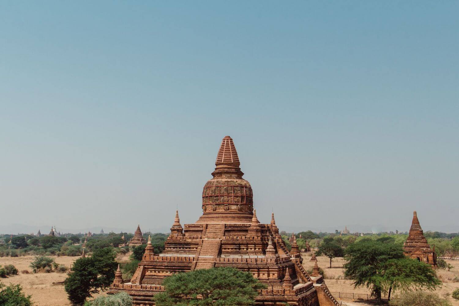 Best Myanmar Itinerary: Photo of an ancient red stone temple in Bagan Myanmar with many other temples in the distance. Photo taken by Ryan Brown of Lost Boy Memoirs, edited in Lightroom.