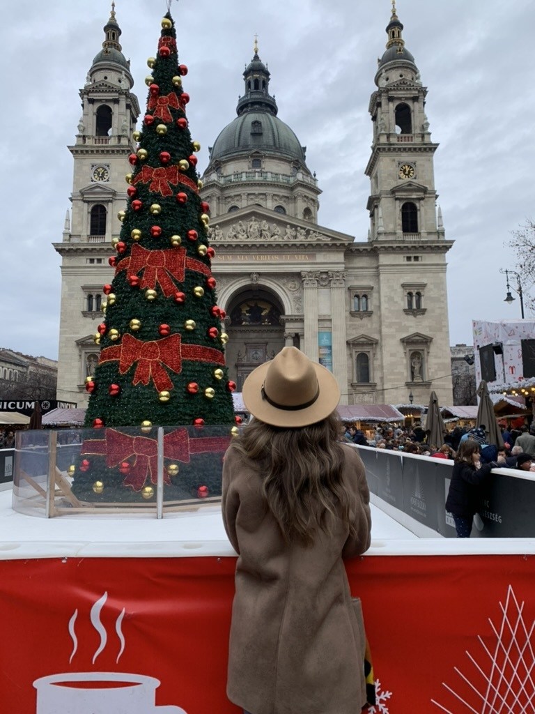 Woman in a winter coat and hat admiring the Christmas tree at the Budapest Christmas market